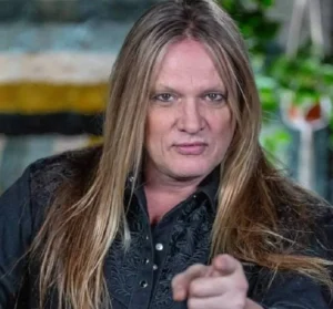 Sebastian Bach is making a hand gesture.