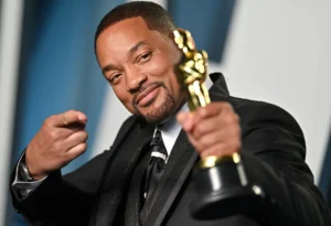 Will Smith is pointing at the trophy.