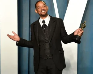 Will Smith is laughing, holding a trophy in his hand.
