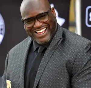 Shaquille O'Neal is laughing while wearing glasses.