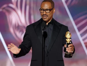 Eddie Murphy is speaking with an award in his hand.