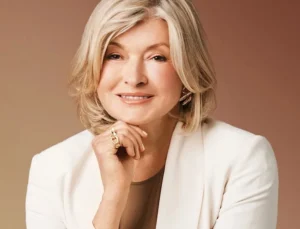 Martha Stewart is laughing with her hands over her face.