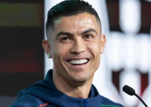 Cristiano Ronaldo laughs while speaking into the mic.