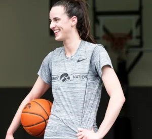 Kaitlyn Clarke is laughing while holding a basketball.