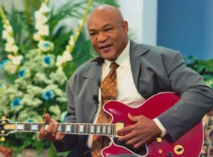 George Foreman is playing the guitar.