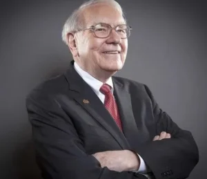 Warren Buffett is laughing with his hands folded.