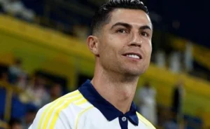Cristiano Ronaldo is standing on the pitch smiling.