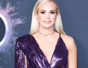 Carrie Underwood is laughing while wearing a bold outfit.