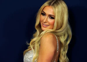 Paris Hilton is standing with style and smiling.