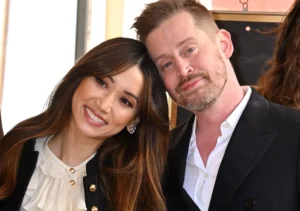 Macaulay Culkin stands with his wife.