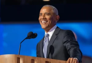 Barack Obama is laughing while speaking into the microphone.