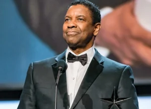Denzel Washington speaks into the mic while accepting an award at the show.