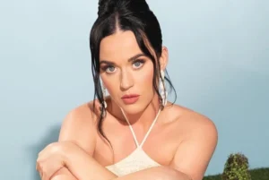 Katy Perry looks on in surprise with folded hands.