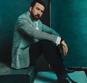 Nicolas Cage is sitting on the ground.
