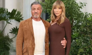 Sylvester Stallone is smiling with his hand on the girl's waist.