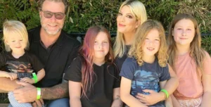 Tori Spelling sits laughing with her husband and four children.