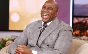 Magic Johnson is sitting on the couch, laughing.