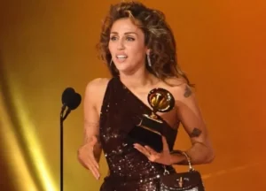Miley Cyrus stands in front of the microphone holding the award.