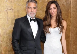 George Clooney is smiling while standing next to his wife.