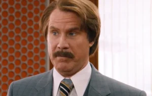 Will Ferrell looks on in surprise, wearing a pantsuit.