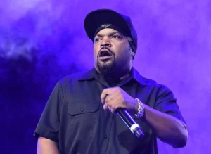 Ice Cube is holding a microphone and singing.
