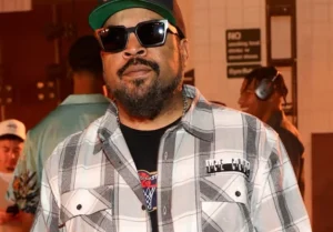 Ice Cube is standing with his glasses on.
