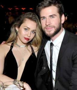 Miley Cyrus is wearing sexy clothes with a guy looking at her breasts.