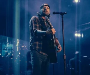 Morgan Wallen is singing while playing the guitar.