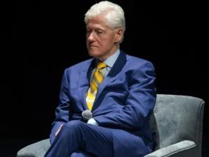 Bill Clinton sits on the couch to talk to the media.