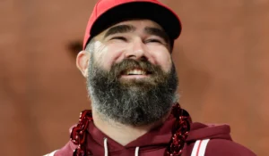 Jason Kelce is laughing while wearing a red sweater.