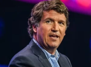 Tucker Carlson is talking while looking to one side.