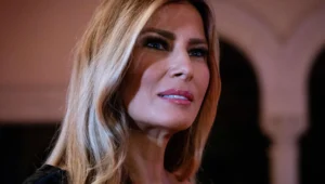 Melania Trump is smiling in a black suit.