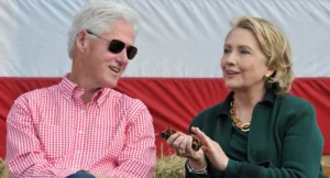 Hillary Clinton laughs while talking to a man outside.