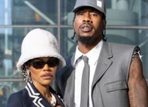 Iman Shumpert stands next to a girl wearing a hat.