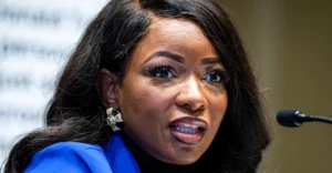 Jasmine Crockett is speaking into a microphone wearing a blue coat.