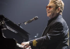 Elton John Mike is singing instead of playing the piano in his own style.