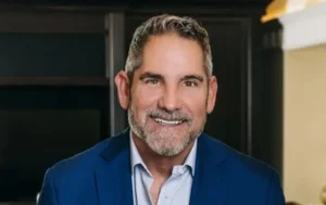 Grant Cardone is smiling, wearing a blue coat.