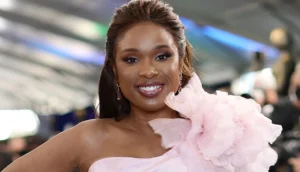 Jennifer Hudson is smiling in a pink floral suit.