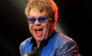 Elton John is singing into the microphone.