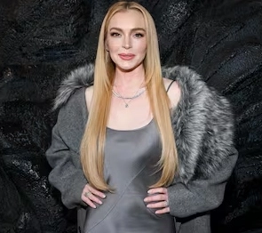 Lindsay Lohan is smiling with her hands on her body.