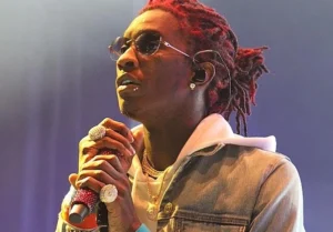Young Thug is holding a microphone and singing.