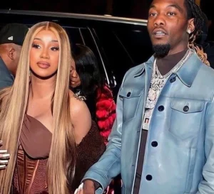 Offset is standing, wearing a blue jacket, holding his wife's hand.
