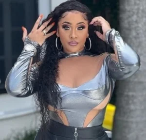 Natalie Nunn is standing outside, doing her hair with her hands.