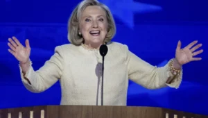 Hillary Clinton raises her hands while speaking into the microphone.