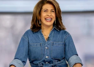 Smiling woman in a denim shirt sitting indoors during a talk show appearance.