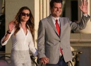 Matt Gaetz is laughing while holding the girl's hand and both are gesturing with their hands.