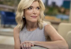 Megyn Kelly is sitting on the couch, looking up and smiling.
