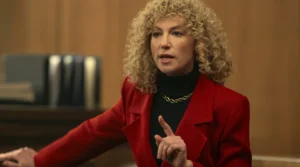 Leslie Abramson is speaking wearing a red coat.