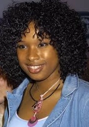 Jennifer Hudson is laughing, wearing a blue coat and a chain around her neck.