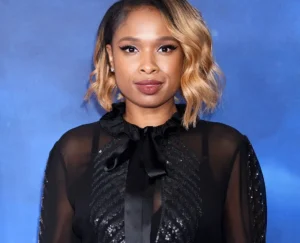 Jennifer Hudson is smiling in a black suit.